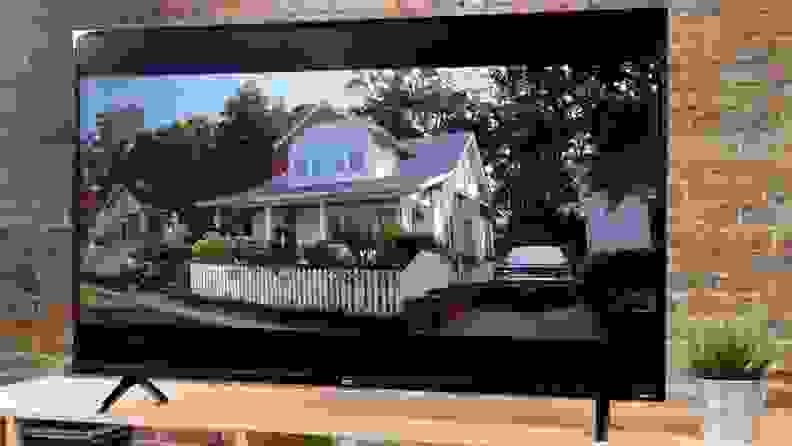 A TV showing a picturesque home against a brick background.