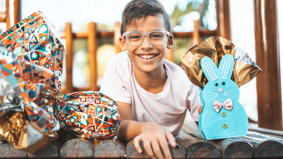 A child poses with a couple wrapped Easter presents.