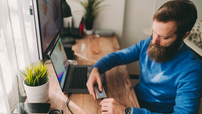 A person connecting a cord to a computer desktop device.