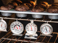 Four of the best oven thermometers Reviewed tested hang inside an oven under a tray of chocolate muffins.