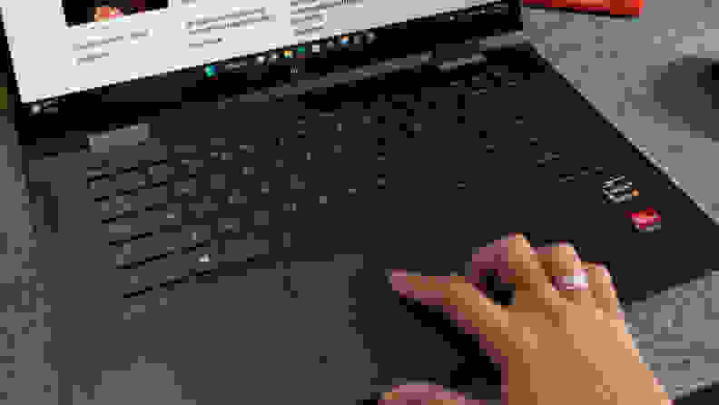 A hand touching the laptops trackpad.