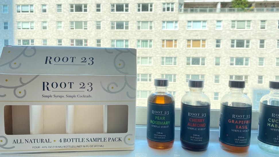 four syrup bottles by white packaging against a city background