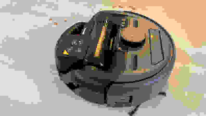 A black robot vacuum on a tile floor