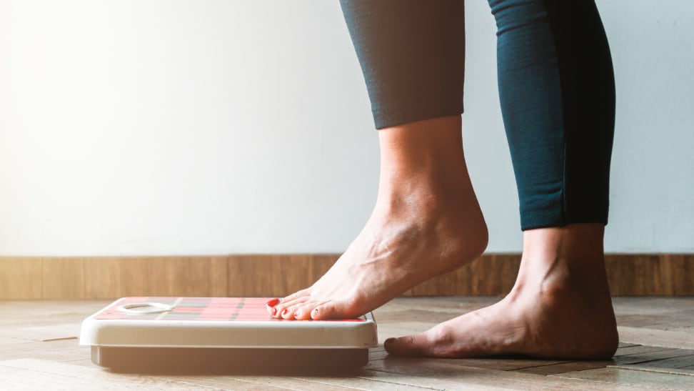 person in black leggings stepping on a scale