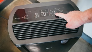 A person adjusts the settings on a black LG Puricare dehumidifier.