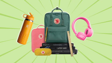 On a light green background: An orange HydroFlask water bottle, one pink and one green Fjallraven backpack, a pair of pink headphones, and a stack of notebooks.