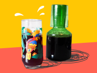 A colorful glass filled with iced hibiscus tea next to a green glass carafe filled with more of the same.