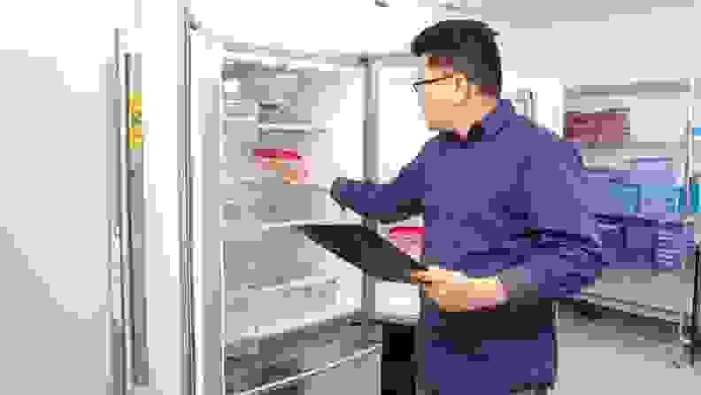Lab technician placing ballast container inside of refrigerator on shelf.