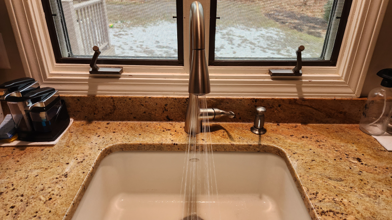 Moen Georgene Kitchen Faucet in modern kitchen setting with water flowing from nozzle.