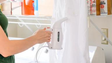 A person using a steamer on a white shirt.