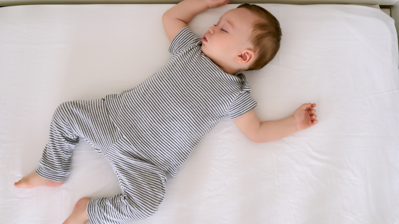 A baby sleeps in a white crib