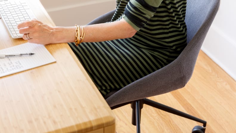A person sitting in a desk chair working at a computer