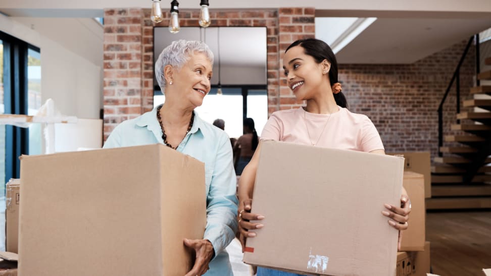 A parent and child move into a home with cardboard boxes.