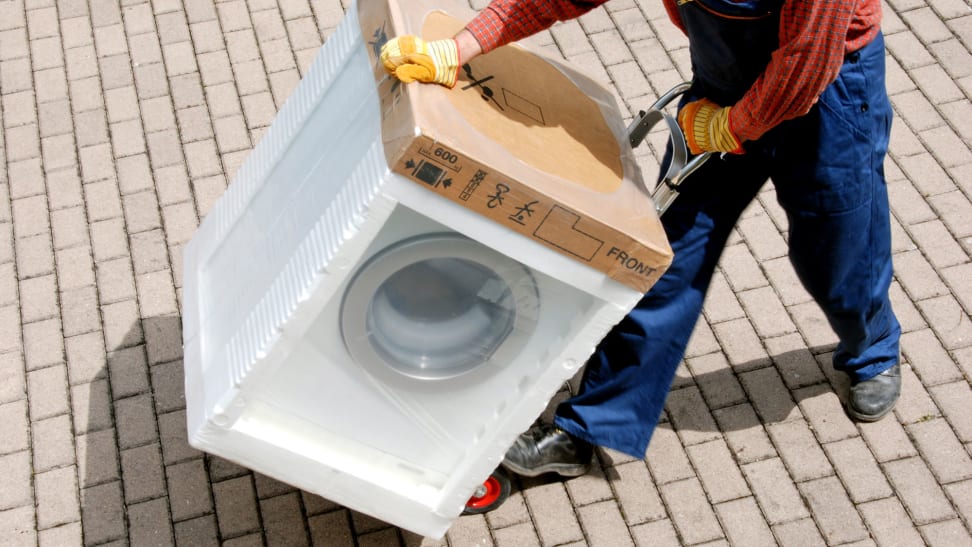 A delivery crew member is moving an appliance on a dolly