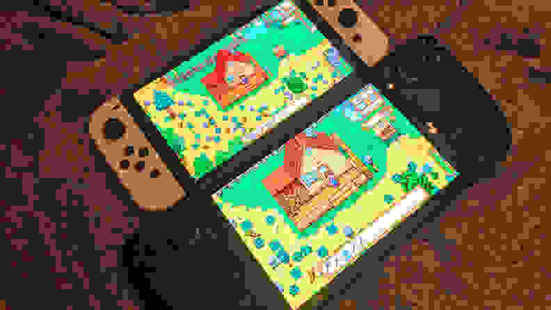 Two handheld gaming consoles next to one another on top of textured gray fabric