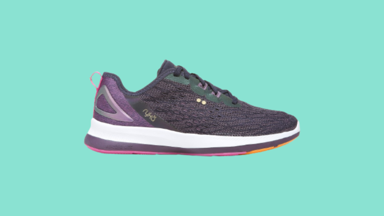 A black and purple sneaker against a green background.