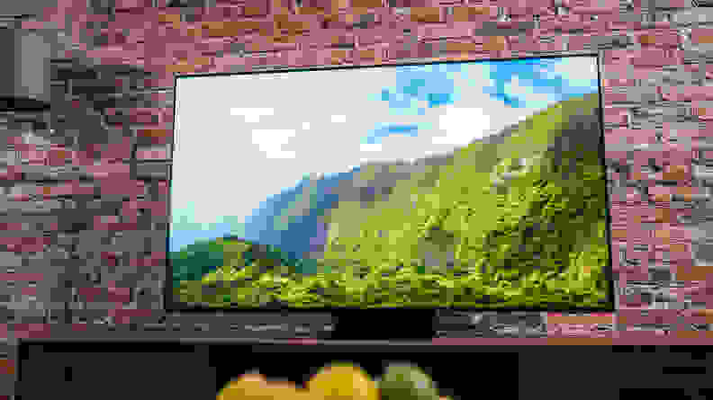 TV shows a mountain range, green against a blue sky, while clouds float overhead