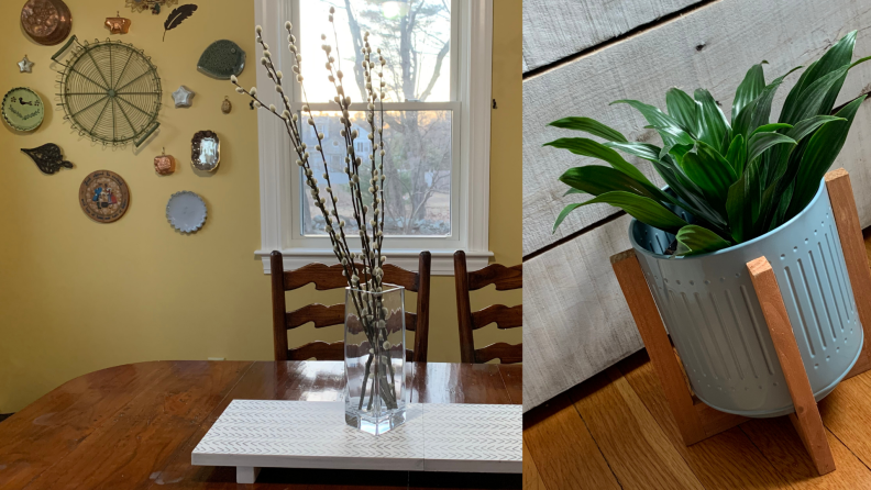 一个有柳枝的花瓶站在一个木制的桌子上，旁边是一个蓝色的金属花盆，里面有一株植物