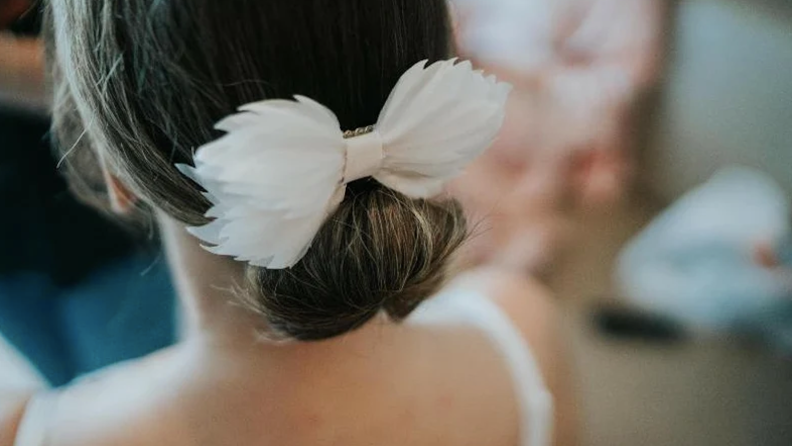 Person wearing white fabric bow in bun.