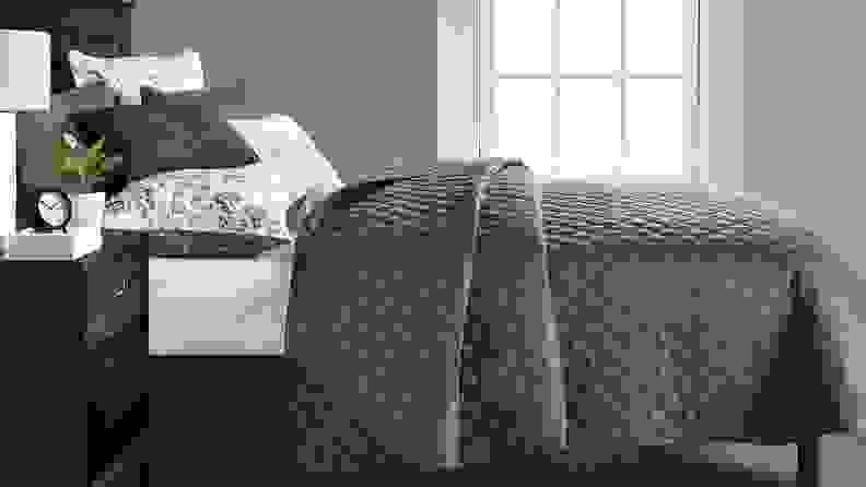 Gray and white comforter set on bed in bedroom.