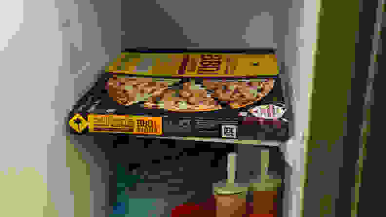 A shot of a standard 12" pizza box crammed onto the 12"-wide freezer shelf of the Samsung RS27T5200SR side-by-side refrigerator.
