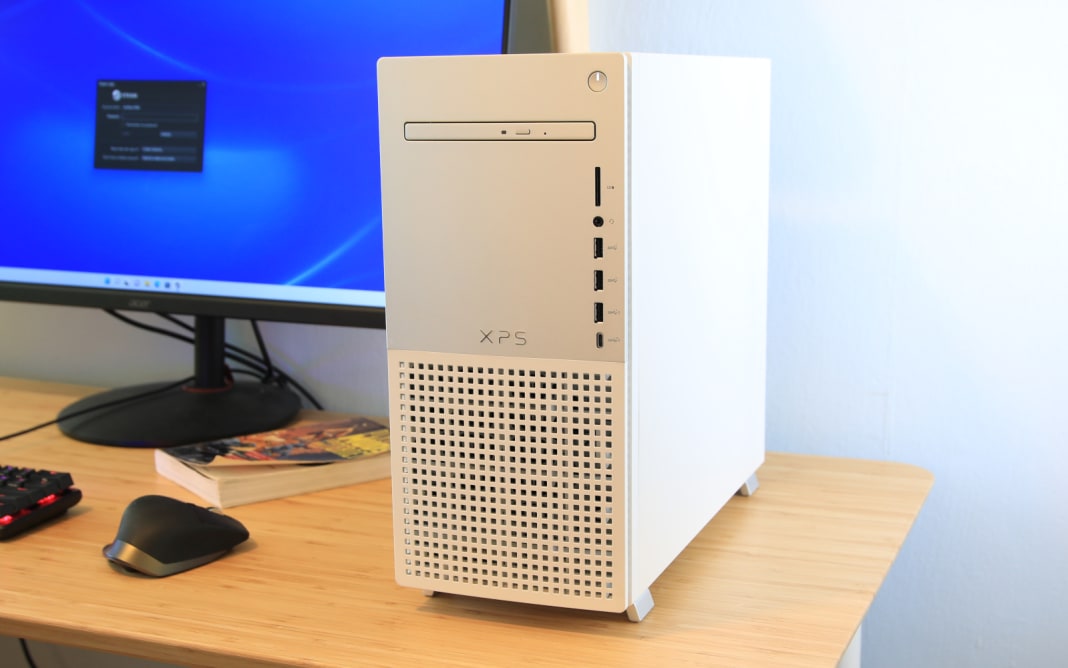 A white Dell desktop tower sits on top of a desk along with a computer monitor.