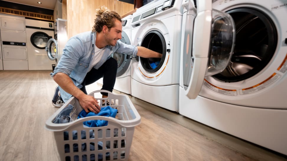 A customer at a self-service laundromat loads a washing machine.