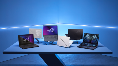 Six Asus laptops in black, gray, and white arrayed on a sleek countertop in a blue room with a string of LED light shining in the background.