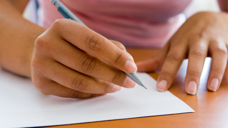 Stock image of a pair of hands preparing to write on a blank piece of printer paper.