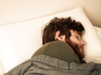 Our photographer's model sleeps soundly (or pretends to) on a large, soft white pillow.