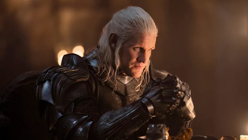 An image of Matt Smith in "House of the Dragon" season 2 as his character Daemon Targaryen. Daemon wears armor, and stares pensively ahead.