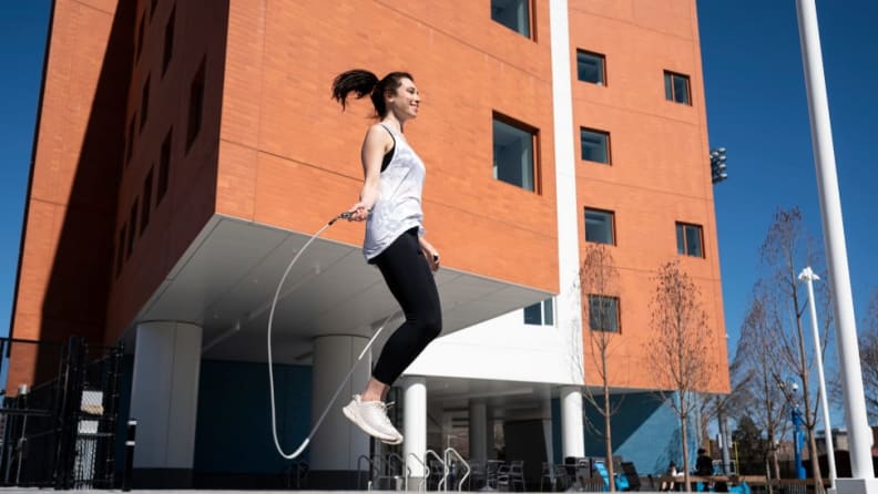 A woman jumping with a jump rope outside.