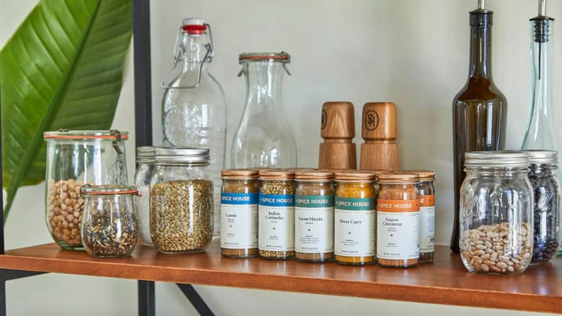 A shelf with glass jars, bottles, and several Spice House jars.
