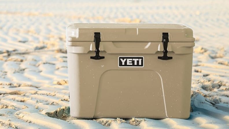 A YETI Tundra 35 cooler with 35-liter capacity is seen either on a sandy beach or in the middle of a dessert.