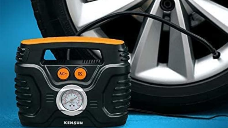 Mini compressor in front of car tire on blue background