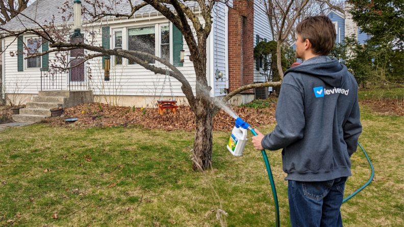 A person sprays insecticide on their front lawn.