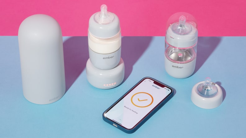 The Ember Baby Bottle System next to a smart phone on a blue and pink background.