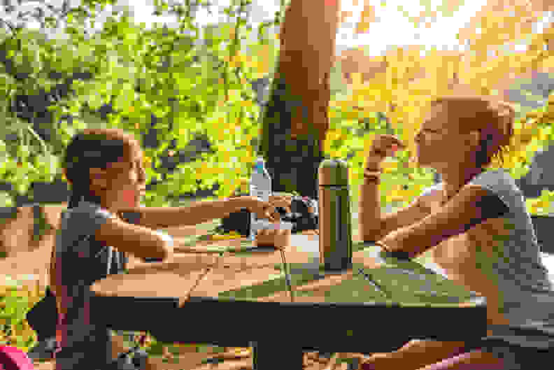 Woman and kid sit at table and share snacks