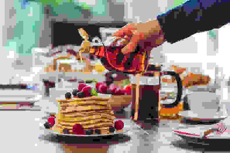 Maple syrup pouring over a stack of pancakes