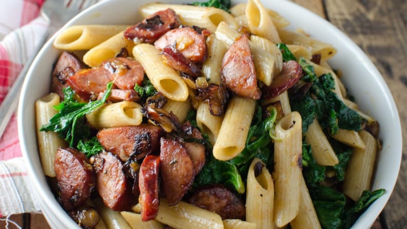 A bowl of whole wheat pasta with spicy chorizo and kale.