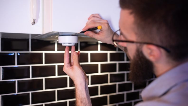 A person installing a smoke detector in their home.