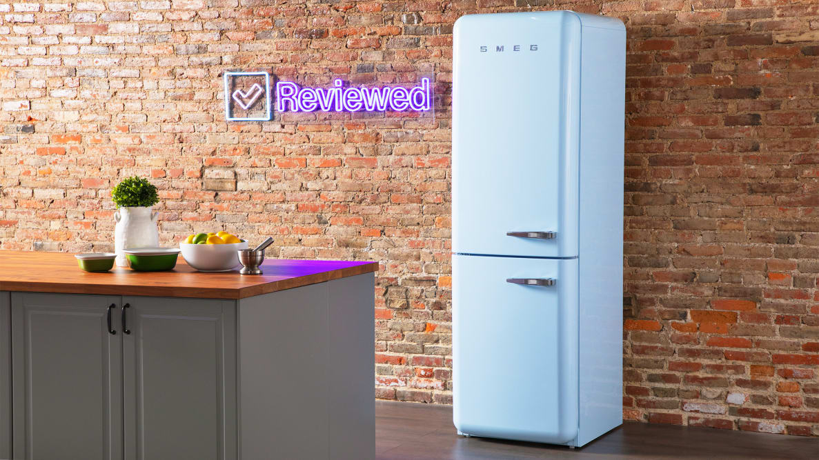 A tall blue Smeg column refrigerator stands in front of a brick wall