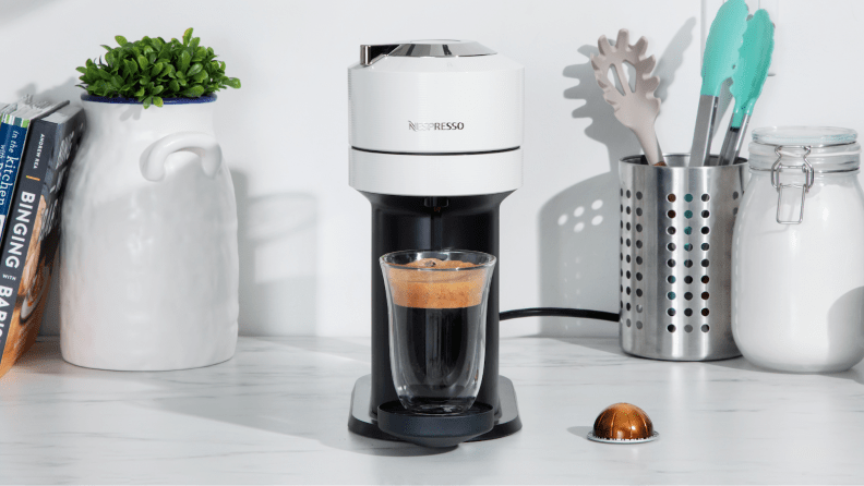 Nespresso Vertuo Next with a filled cup of Nespresso coffee on a white marble countertop
