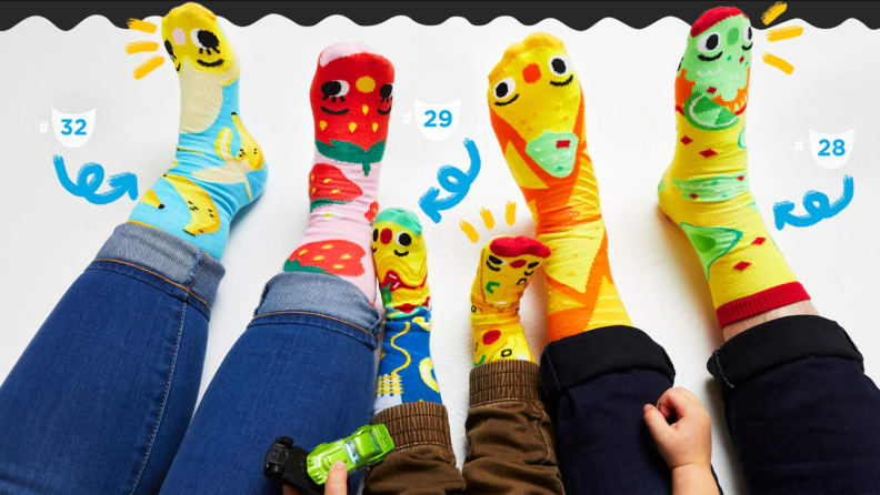 Three pairs of feet (2 adults and one kid in the middle) wearing colorful monster socks