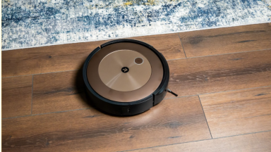 The iRobot j9+ on a wooden floor next to a carpet.