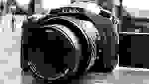 Monochrome close-up of a Lumix superzoom digital camera.