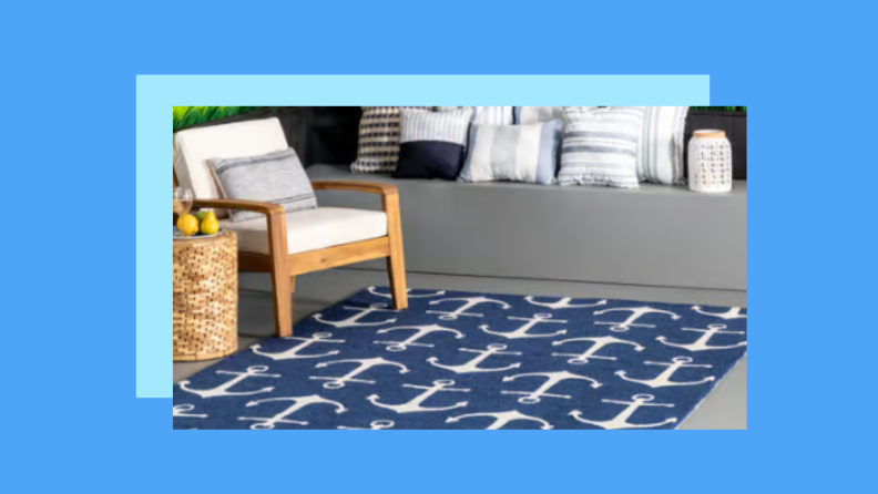 An anchor print rug on a patio against a blue background.