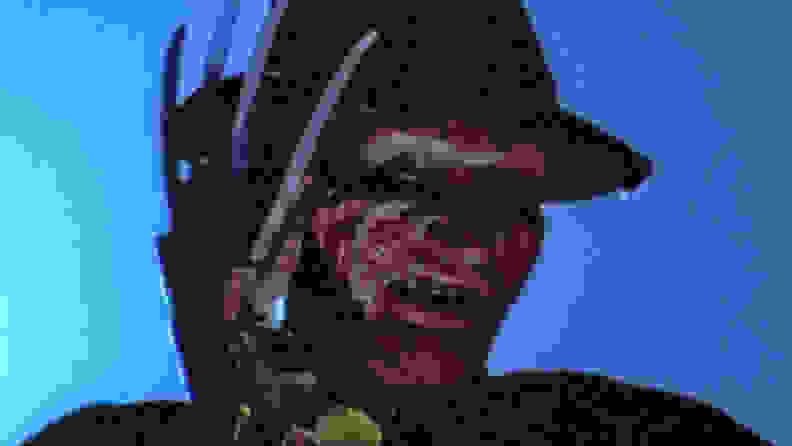 A close-up of Freddy Krueger, with bladed glove partially covering his face, from