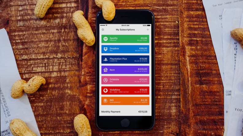 An iPhone resting on a bed of wood with peanuts scattered about, with an iPhone in the center showing Bobby's home screen with a list of subscriptions.