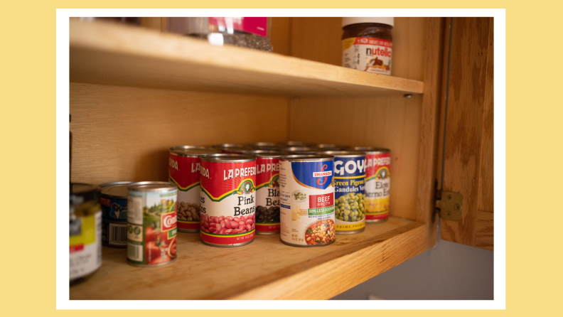 Canned good stored on wooden shelves in kitchen.